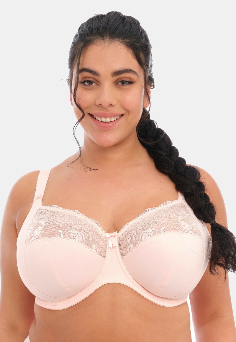 Soutien-gorge rose clair avec des bonnets en dentelle à motif floral, en tissu doux, avec armatures de soutien et bretelles réglables. Détail de nœud au centre.