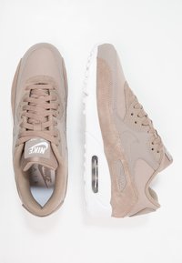 Béžové tenisky Nike Air Max 90 z semiše a síťoviny, s bílou podrážkou, texturovanými prvky a viditelnou vzduchovou jednotkou.
