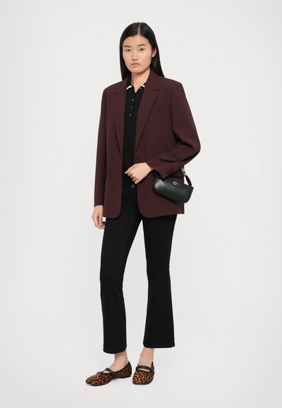 Burgundy blazer over a black polo, paired with black flared jeans and leopard print flats. Black handbag with gold hardware.