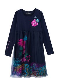 Robe bleu marine à manches longues avec broderie florale rose et bleue sur la poitrine, superposition de jupe florale multicolore vibrante, et texte "Crois en toi" sur la manche.