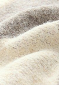 Vilnonis audinys, pasižymintis švelniais, šviesiais grietinėlės atspalviais su subtiliais rožiniais taškeliais. tekstūruota, pūkuota paviršius su švelniais raukšlėmis ir bangomis.