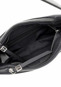 Mustast nahast käekott, mille lukk on lahti ja näitab sisekompartmentide ning hõbedaste tõmblukukorvidega logo detaili.