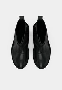 Paire de bottines en cuir noir avec fermetures éclair à l’avant et languettes, vues de dessus sur fond blanc uni.