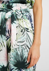 Spodnie w kwiatowy wzór z lekkiego materiału, z elastycznym pasem, ozdobione związanym paskiem oraz mieszanką zielonych, różowych i granatowych liści.