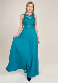 Türkises Abendkleid mit tailliertem Oberteil, das mit aufwendiger Blumen-Spitze und Perlenstickerei verziert ist. Fließender Rock aus leichtem Stoff.