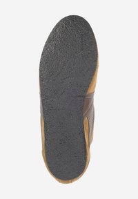 La semelle de la chaussure présente une base en caoutchouc noir texturé avec un dessus en suede tan, rehaussée par des superpositions en cuir marron foncé.