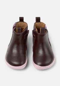 Une paire de bottes pour tout-petits en cuir marron foncé avec des semelles roses et des zips sur le côté, vues de face sur un fond blanc.