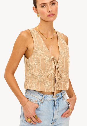 Top court beige avec broderies florales, décolleté en V profond et détail de lien à l'avant. Tissu léger avec une texture lisse et design sans manches.