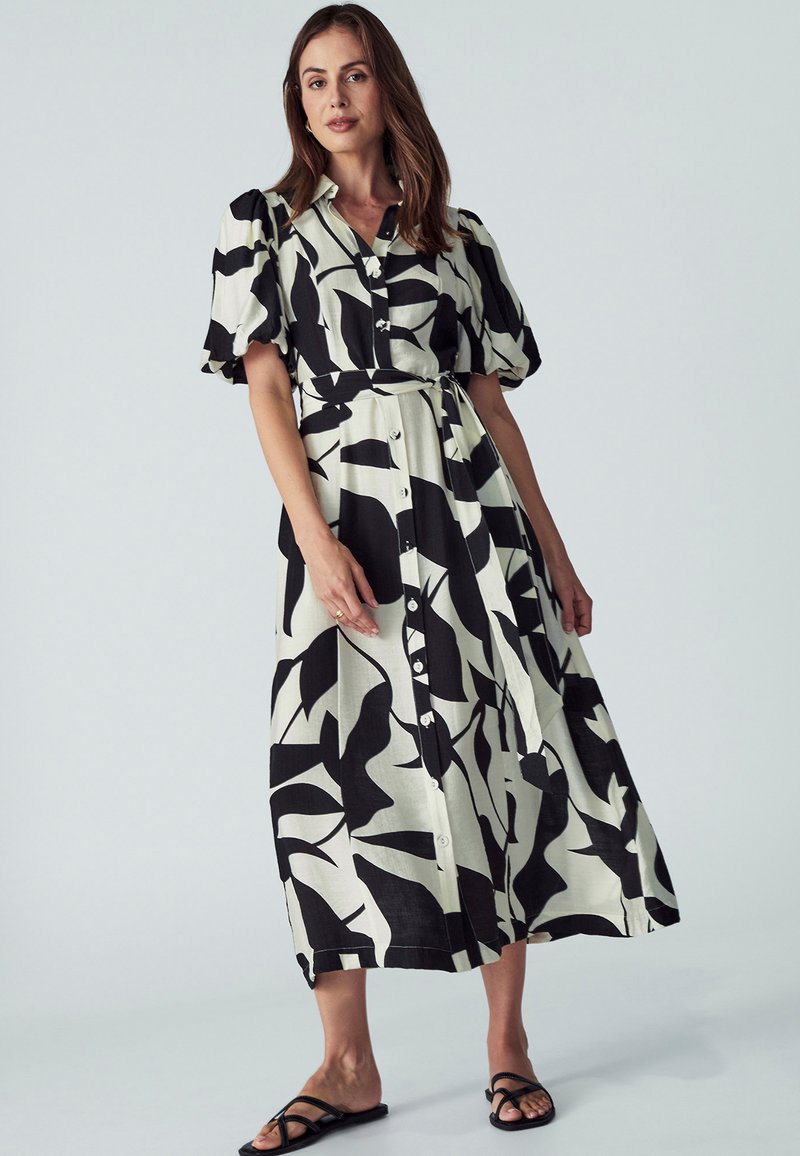 Schwarzes und weißes gemustertes Midikleid mit kurzen Puffärmeln, Knopfleiste und gebundenem Taillenbund. Glattes Material mit einer fließenden Silhouette.