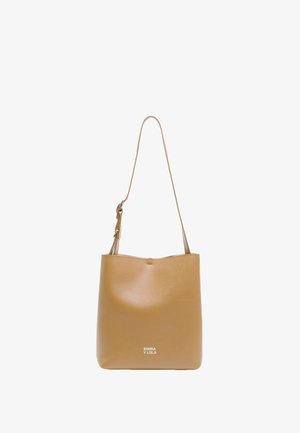 Sac fourre-tout en cuir tan avec une texture lisse, bandoulière réglable et logo en relief à l'avant. Design minimaliste, ouverture sur le dessus.