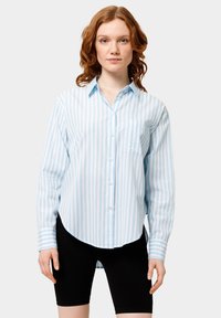 Camicia button-up a righe blu e bianche con una sola tasca sul petto, orlo arrotondato e maniche lunghe. Realizzata in tessuto leggero.