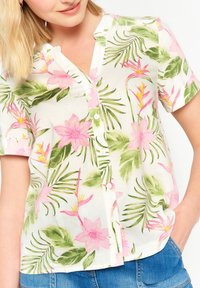 Short-sleeve button-up shirt made from lightweight fabric featuring a white background with green leaves and pink floral patterns.