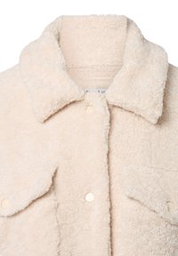 Crèmekleurige, fluffy textuurjas met grote kraag, drukknoopjes en klepzakken op een witte achtergrond.
