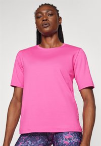 Pink short-sleeve t-shirt made from smooth, stretchy fabric. Round neckline and minimal stitching details, paired with patterned leggings.