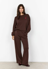 Bruine katoenen sweatshirt en wijde broek set, met een kleine rode hartborduursel op de borst, gladde textuur, relaxte pasvorm.