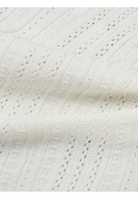 Tissu tricoté blanc avec un motif texturé de rayures verticales alternées et de petits trous ouverts, mettant en valeur une apparence douce et légère.