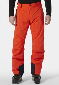 Oranje waterdichte skibroek met een ontspannen pasvorm, voorzien van een marineblauwe accent bij de boorden en een ritszak aan de zijkant.