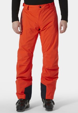 Pantalones de esquí impermeables en color naranja con un ajuste relajado, que cuentan con un acento en azul marino en los puños y un bolsillo lateral con cremallera.
