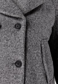 Grijze wollen jas met een gestructureerde stof, grote revers, twee zwarte knopen en een zijzak.