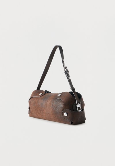 Hnedá textúrovaná kožená kabelka cez rameno so striebrnými gombíkmi a nastaviteľným čiernym pásikom na jednoduchom bielom pozadí.