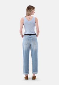 Hellblaues geripptes Tanktop, kombiniert mit lockeren, ausgewaschenen blauen Jeans, am Saum hochgekrempelt; getragen mit braunen Wildlederschuhen.