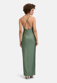 Sukienka maxi w oliwkowym satynie, z niskim plecami i krzyżującymi się ramiączkami oraz dopasowanym krojem. Gładka struktura, minimalistyczny design.