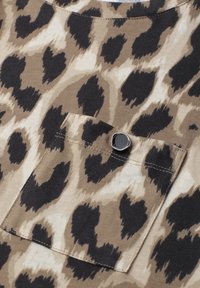 Brown and beige leopard print fabric with a small pocket featuring a shiny black button on the upper edge.