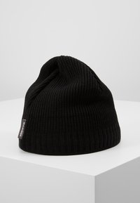 Black knit beanie with a ribbed texture. Features a small fabric tag on the side. Cap shape with a slouchy top design.