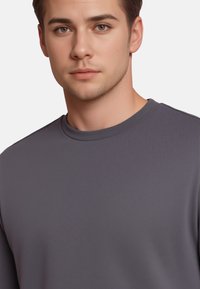 Γκρίζο μακρυμάνικο μπλουζάκι με στρογγυλή λαιμόκοψη, με λεία υφή και μίνιμαλ σχέδιο, που αναδεικνύει την ελαστικότητα και την εφαρμογή του υφάσματος.