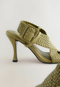 Sandală verde cu toc înalt, cu un brâu lat și o cataramă mare rectangulară, talpă netedă și toc subțire stilettos.