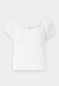 Camicia bianca in cotone con maniche corte a palloncino, scollatura quadrata e apertura con bottoni. Presenta dettagli in pizzo con motivi floreali e arricciatura elastica.