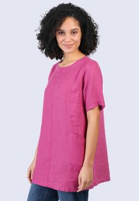Pink linen tunic top with short sleeves and a round neckline, featuring a side pocket and minimal stitching details.
