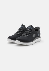 Black mesh athletic shoes with a textured upper, white sole, elastic laces, and Skechers logo in blue on the sides.