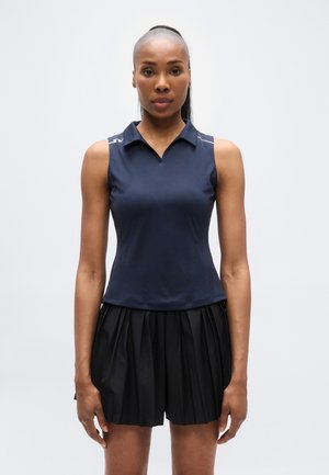 Tumesinine varrukateta polosärk kraega kaelusega, mida on kombineeritud volditud musta seelikuga. Sile kangas, kehatriibuline ja ilma nähtavate mustriteta.