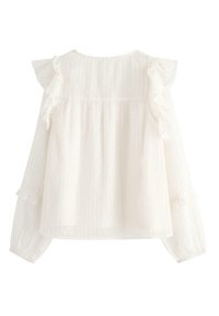 Hvid bluse med et tekstureret stof og subtile striber, rynke-detaljer på ærmerne og en løs, svævende silhuet.