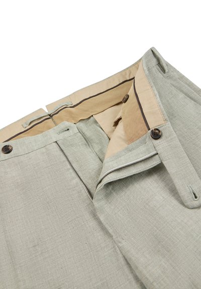 Pantalones gris claro con cremallera abierta, cierre de botón, forro interior beige y trabillas visibles sobre un fondo blanco.