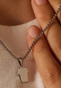Zilveren ketting met een hanger in de vorm van een T-shirt. De hanger heeft een gepolijste oppervlakte en is bevestigd met een eenvoudige bail.