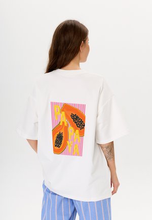 Witte oversize t-shirt met een kleurrafische afbeelding van papaja's en het woord "PAPAYA" op de achterkant, met roze gestreepte achtergrondaccenten.