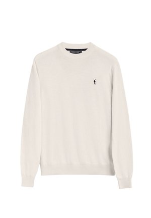 Suéter beige claro hecho de material suave, con cuello redondo, mangas largas y un pequeño logo oscuro en el lado izquierdo del pecho.