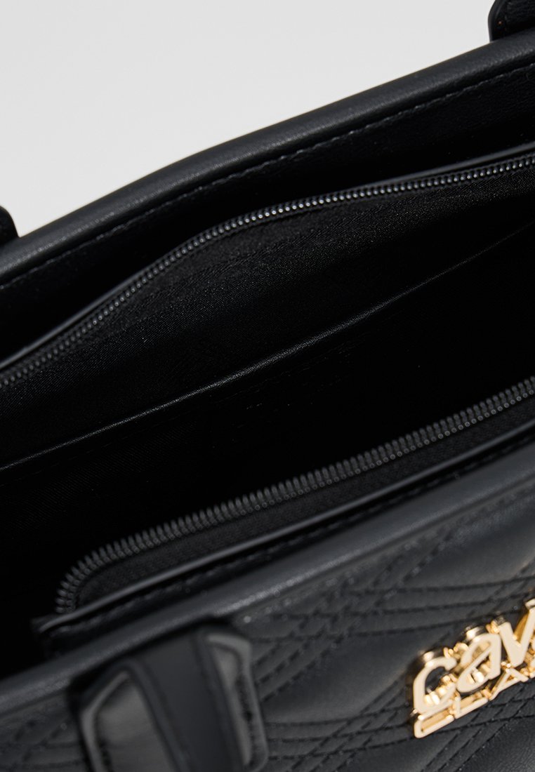 Borsa a tracolla nera trapuntata con doppie cerniere che mostrano i compartimenti principali aperti e placca con logo dorato sul davanti.