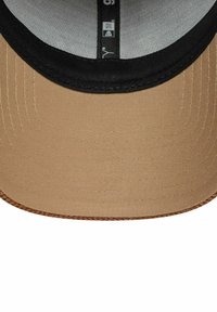 Beige Kappe mit einem schwarzen Schirm, aus strukturiertem Stoff, mit subtilen Nähdetails und einem glatten Innenfutter. Runde Naht auf der Unterseite.