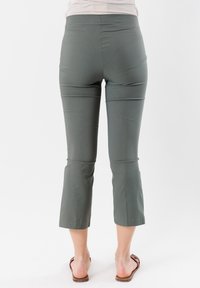 Pantaloni capri grigi con una texture liscia e un design aderente, caratterizzati da una vita media e una lunghezza cropped, abbinati a sandali marroni.