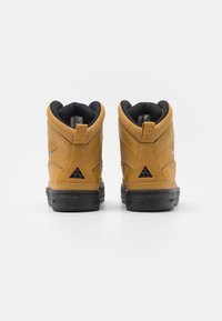 Höga sneakers i tan läder med svarta accenter. Har en vadderad krage, texturerade ytor och en stadig svart gummisula.