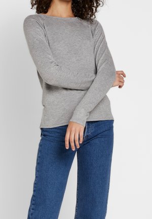 Grijze lange mouwen trui met een ronde hals, gemaakt van zacht materiaal. Gestyld met blauwe denim jeans, met een ontspannen pasvorm.