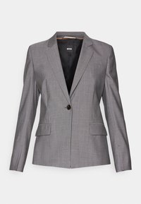 Blazer gris sur mesure avec une fermeture à un bouton, deux poches avant et un col à revers cranté. Confectionné en tissu texturé avec une doublure intérieure lisse.