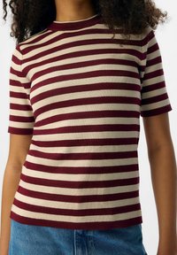 Top à rayures à manches courtes en bordeaux et crème. Présente une texture côtelée et un col rond. Coupe droite, fabriqué à partir d'un tissu extensible.