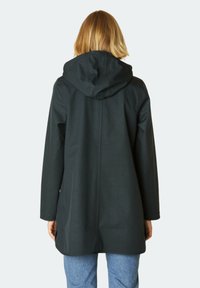 Chaqueta negra con capucha de textura suave, con un corte holgado, mangas largas y un diseño de espalda recta. Accentuada con detalles de hardware mínimos.