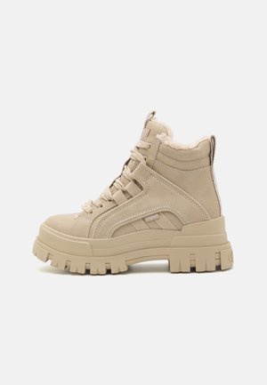Zapatillas altas beige con un acabado de ante texturizado, ojales reforzados y una suela de goma gruesa. Detalles de forro suave y doble tirador.