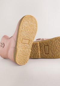 Bottines en cuir rose avec semelles en caoutchouc texturées, présentant un bout arrondi et des découpes latérales discrètes pour la ventilation.