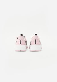 Vaaleanpunaiset urheilusandaalit, joissa on sileä päällinen, mustat aksentit, vetotai ja valkoiset pohjat. Takaa näkyy kontrastoivat värit ja muotoilulinjat.